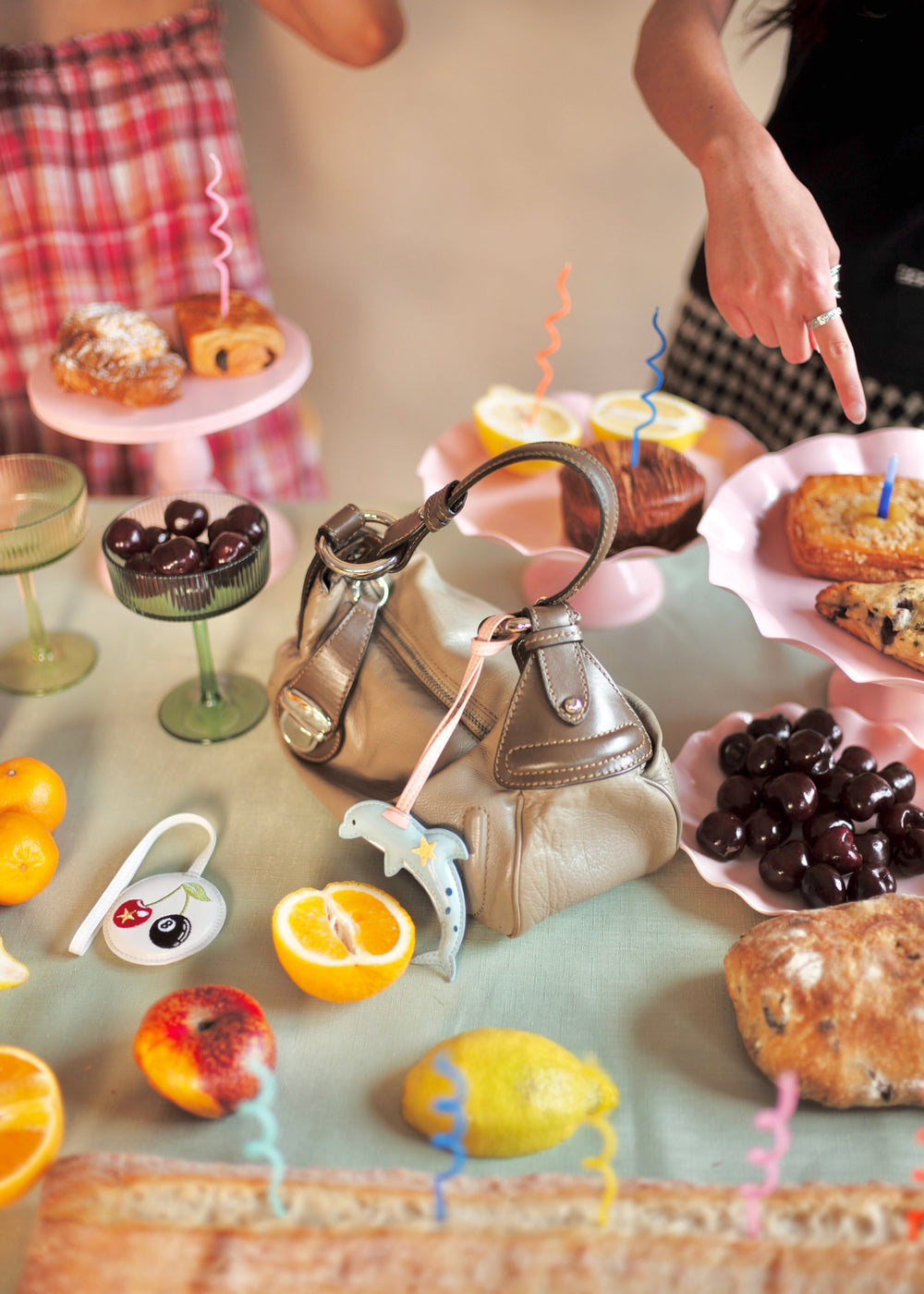 Tea party setup with teapot, pastries, and fruit on a table.