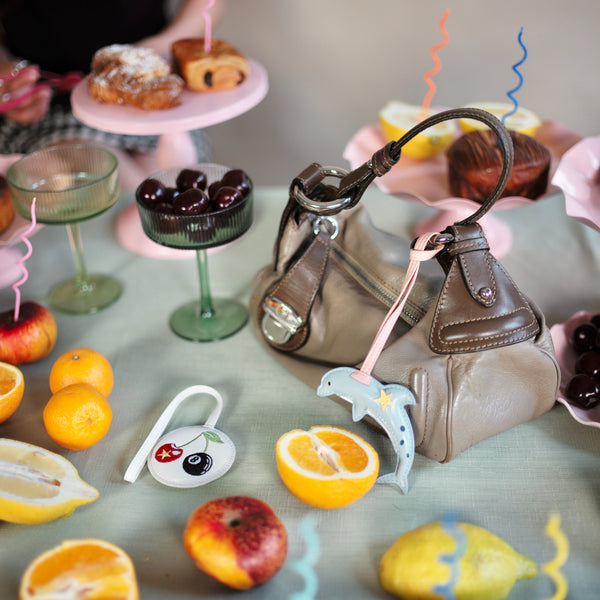 Table setting with fruits, a handbag, and decorative elements on a gray surface.