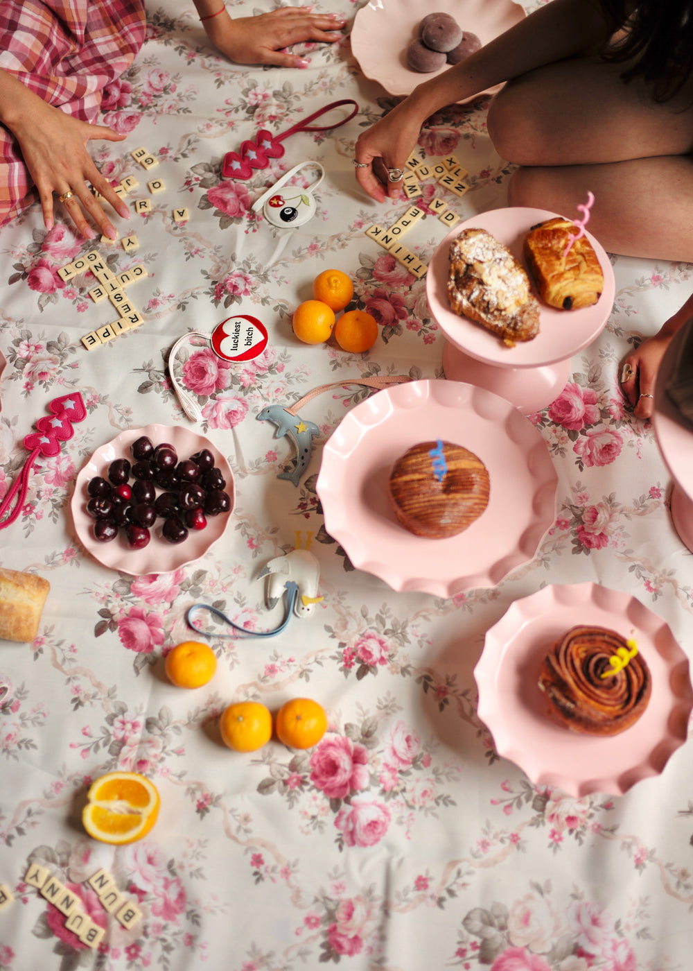 People sitting around a floral tablecloth with pastries and fruit